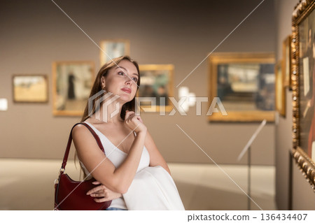 Girl view pictures and icons in museum hall 136434407