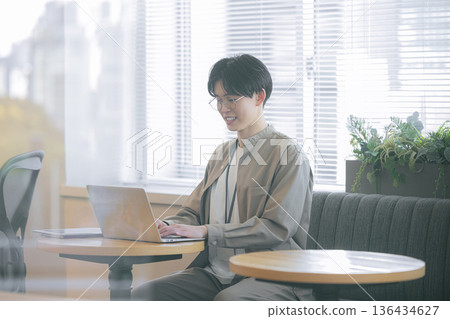 一個男人坐在沙發上使用電腦 136434627