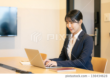 Smiling young woman using a laptop Smiling young woman using a laptop 136434628
