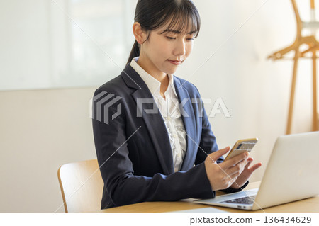 Young business woman operating a smartphone Young business woman operating a smartphone 136434629
