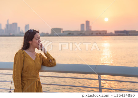 Portrait of Fashionable Asian Woman in Yellow Dress at Sunset with Abu Dhabi Skyline 136434880