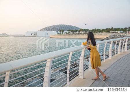 Rear View of Fashionable Young Woman in Yellow Outfit Outside Louvre Abu Dhabi at Sunset Rear View of Fashionable Young Woman in Yellow Outfit Outside Louvre Abu Dhabi at Sunset 136434884