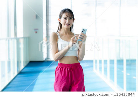 在健身房用智慧型手機的女人 在健身房用智慧型手機的女人 136435044