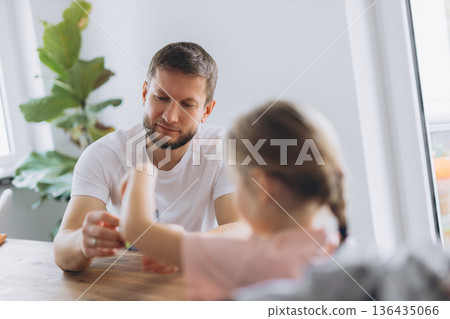 Father and daughter play with a puzzle cube at home, sitting at a wooden table and enjoying mindful time together Father and daughter play with a puzzle cube at home, sitting at a wooden table and enjoying mindful time together 136435066