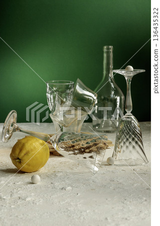 Dramatic still life with broken crystal wine glass, scattered salt and lemon on white table. Dramatic still life with broken crystal wine glass, scattered salt and lemon on white table. 136435322