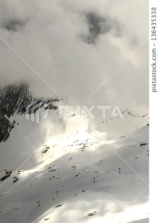 Vertical view of dramatic light beam hitting snowy Zugspitze mountain slope through clouds. Vertical view of dramatic light beam hitting snowy Zugspitze mountain slope through clouds. 136435338