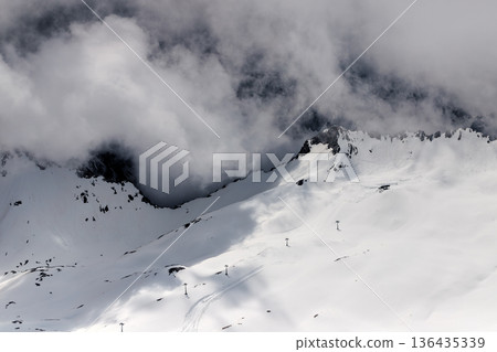 Dramatic winter landscape of Zugspitze mountain ridge covered in snow and heavy clouds. Dramatic winter landscape of Zugspitze mountain ridge covered in snow and heavy clouds. 136435339