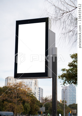 Blank white billboard screen on a street lamp pole, ready for custom outdoor city advertising, communication, and marketing message mockups in an urban setting 136435412