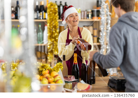 Young female seller offers whiskey to buyer 136435760