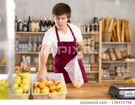 Male seller weighing apples Male seller weighing apples 136435796