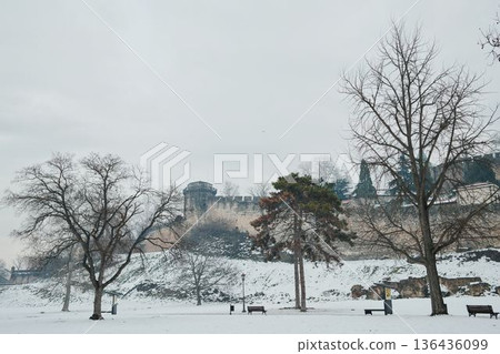 View of ancient Kalemegdan fortress walls through bare winter trees, blending historic stone architecture with natural park surroundings View of ancient Kalemegdan fortress walls through bare winter trees, blending historic stone architecture with natural park surroundings 136436099