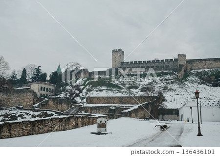 Long medieval fortress walls running along a snowy hillside, emphasizing defensive architecture, historic scale, and winter city landscape 136436101