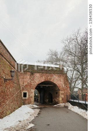 Brick fortress entrance in Kalemegdan, Belgrade with arched passage and winter path, highlighting medieval military architecture and historic urban landscape 136436530