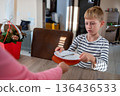 Boy handing a plate to an adult at the table, child helping with household chores at home 136436533