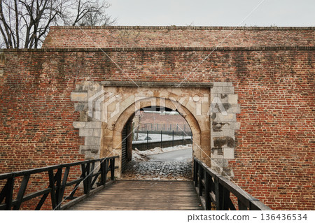 Stone gate with wooden bridge leading through historic fortress wall in Kalemegdan, Belgrade, showing medieval architecture, symmetry and winter urban heritage Stone gate with wooden bridge leading through historic fortress wall in Kalemegdan, Belgrade, showing medieval architecture, symmetry and winter urban heritage 136436534