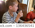 Elementary age boy drinking water at the table indoors, casual daily life moment 136436541