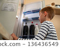 Young boy looking into open refrigerator at home, everyday domestic lifestyle 136436549