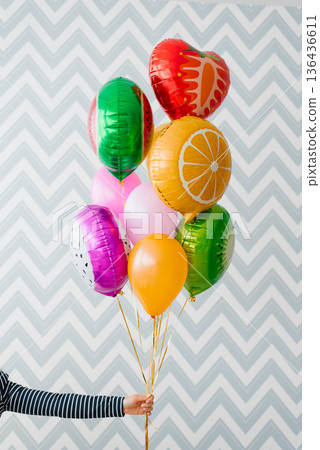 Hand Holding Colorful Fruit And Heart Balloons Hand Holding Colorful Fruit And Heart Balloons 136436611