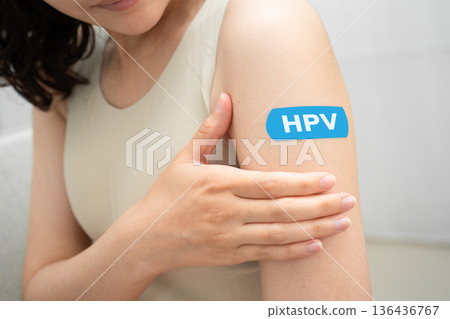 HPV, Human papillomavirus, Asian young woman receiving vaccine with blue bandage. HPV, Human papillomavirus, Asian young woman receiving vaccine with blue bandage. 136436767
