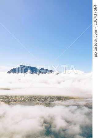 Aerial view of Table mountain peeking above clouds over Cape Town cityscape. Luxury travel destination with iconic landmark. Aerial view of Table mountain peeking above clouds over Cape Town cityscape. Luxury travel destination with iconic landmark. 136437664