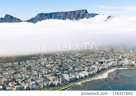 Aerial view of Cape Town city covered by fog with the top of Table mountain visible. South Africa travel and tourism concept. Aerial view of Cape Town city covered by fog with the top of Table mountain visible. South Africa travel and tourism concept. 136437665