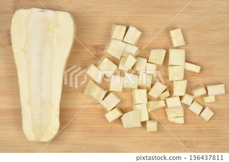 Chopped and halved parsnip on wooden board 136437811