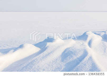 Snow dunes stretch across sunlit winter landscape 136438355