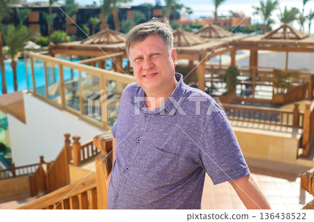 A grown man squints his eyes from the bright sun outside A grown man squints his eyes from the bright sun outside 136438522