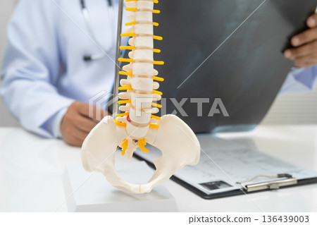 Doctor examining spine bone radiography xray film. Doctor examining spine bone radiography xray film. 136439003