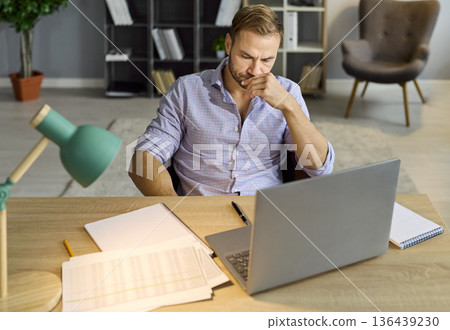 Concerned businessman at laptop analyzing papers and accounting data during audit 136439230