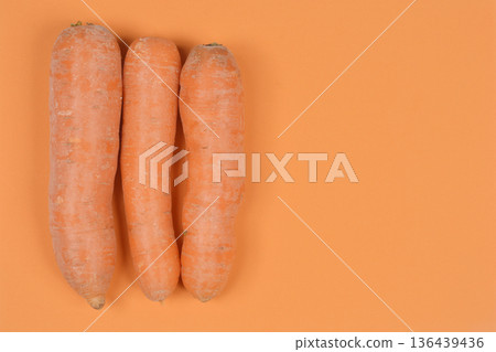 Three fresh carrots on orange background Three fresh carrots on orange background 136439436