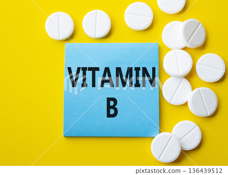 Vitamin B symbol. Concept word Vitamin B on blue note. Beautiful yellow background with pills. Medicine and Vitamin B concept. Copy space Vitamin B symbol. Concept word Vitamin B on blue note. Beautiful yellow background with pills. Medicine and Vitamin B concept. Copy space 136439512
