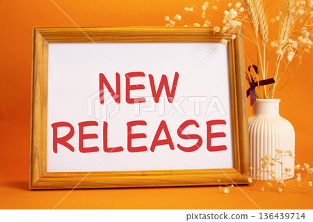 New Release symbol. Concept words New Release on beautiful wooden picture frame. Beautiful orange background with flower vase. Business and New Release concept. Copy space. New Release symbol. Concept words New Release on beautiful wooden picture frame. Beautiful orange background with flower vase. Business and New Release concept. Copy space. 136439714