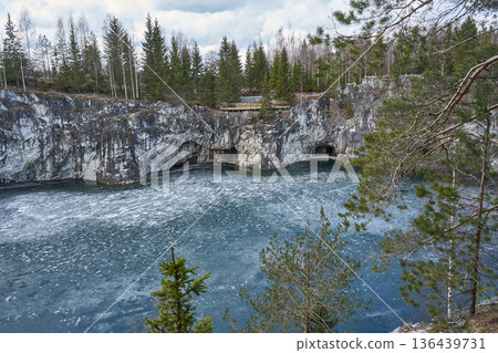 Winter landscape of Ruskeala Mountain Park with frozen lake. Marble canyon and surrounding forest in nature reserve. Outdoor travel. 136439731
