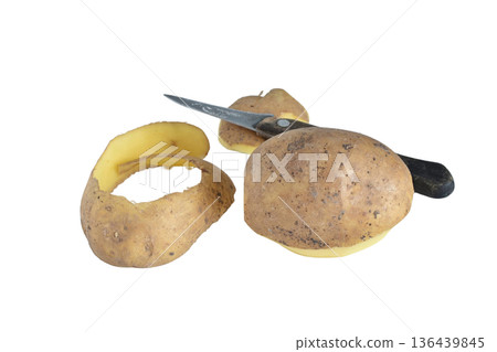 A potato and a potato peel lie next to a knife. 136439845