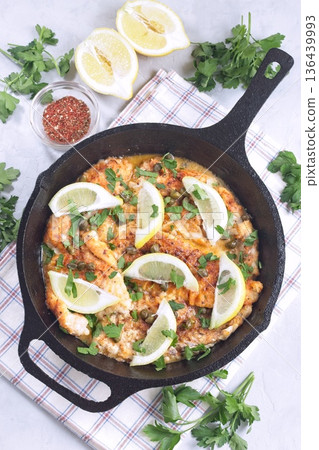 Delicious haddock fish piccata with lemon and capers in cast iron pan, vertical, top view Delicious haddock fish piccata with lemon and capers in cast iron pan, vertical, top view 136439993