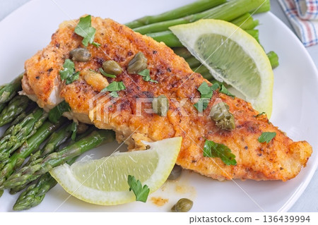 Delicious haddock fish piccata, battered fish fillet with capers, lemon and asparagus, horizontal Delicious haddock fish piccata, battered fish fillet with capers, lemon and asparagus, horizontal 136439994