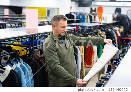 Man browsing clothes at vintage thrift shop, second-hand stylish store Man browsing clothes at vintage thrift shop, second-hand stylish store 136440422