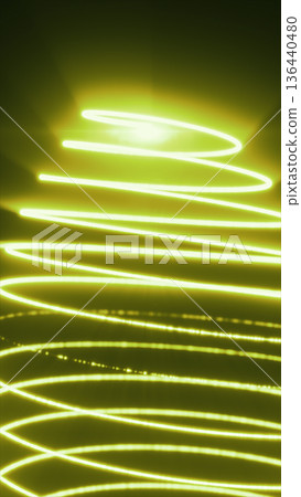Bright yellow glowing spiral streaks swirling across a dark background, creating energetic flowing motion Bright yellow glowing spiral streaks swirling across a dark background, creating energetic flowing motion 136440480