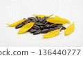 Small mound of sunflower seeds and a few petals on a white background 136440777