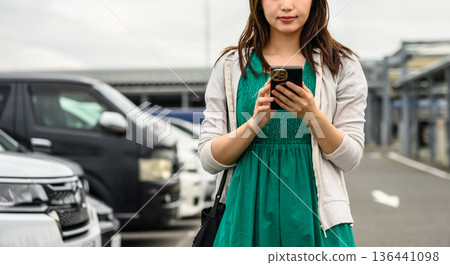 A woman using her smartphone in a parking lot. Photo courtesy of Kansai International Airport (KIX) A woman using her smartphone in a parking lot. Photo courtesy of Kansai International Airport (KIX) 136441098