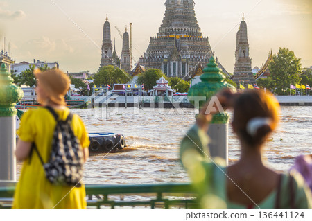 Tourists take photos with their smartphones at Wat Arun Ratchawararam Ratchaworamahawihan during sunset in Bangkok, Thailand. Tourists take photos with their smartphones at Wat Arun Ratchawararam Ratchaworamahawihan during sunset in Bangkok, Thailand. 136441124