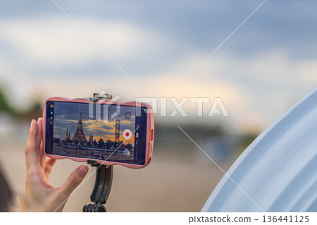 Tourists take photos with their smartphones at Wat Arun Ratchawararam Ratchaworamahawihan during sunset in Bangkok, Thailand. Tourists take photos with their smartphones at Wat Arun Ratchawararam Ratchaworamahawihan during sunset in Bangkok, Thailand. 136441125