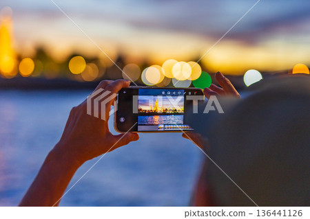 Tourists take photos with their smartphones at Wat Arun Ratchawararam Ratchaworamahawihan during sunset in Bangkok, Thailand. Tourists take photos with their smartphones at Wat Arun Ratchawararam Ratchaworamahawihan during sunset in Bangkok, Thailand. 136441126
