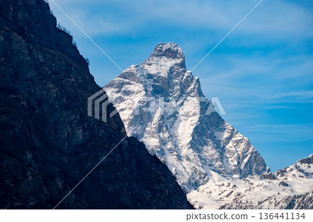 Iconic Matterhorn peak in the Swiss Alps, a majestic snow-capped mountain against a blue sky Iconic Matterhorn peak in the Swiss Alps, a majestic snow-capped mountain against a blue sky 136441134