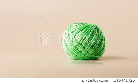 A ball of green recycled polyester synthetic fabric on beige background. Green living, plastic recycling, reuse A ball of green recycled polyester synthetic fabric on beige background. Green living, plastic recycling, reuse 136441420