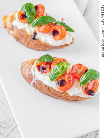 Gourmet bruschetta with stracciatella cherry tomatoes basil and balsamic on bright rustic background Gourmet bruschetta with stracciatella cherry tomatoes basil and balsamic on bright rustic background 136441835