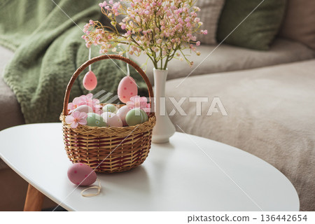 Easter Basket with Ester Eggs, Plush Bunny and Spring Decor on White Table intoCozy Living Room Easter Basket with Ester Eggs, Plush Bunny and Spring Decor on White Table intoCozy Living Room 136442654