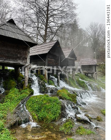 Traditional wooden water mills in Jajce, Bosnia, surrounded by flowing streams and mossy rocks, creating a scenic rural landscape with heritage and nature harmony Traditional wooden water mills in Jajce, Bosnia, surrounded by flowing streams and mossy rocks, creating a scenic rural landscape with heritage and nature harmony 136443191