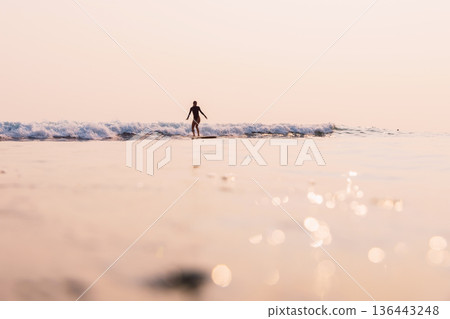 Surfing woman on surfboard riding foam wave on sunrise . 136443248